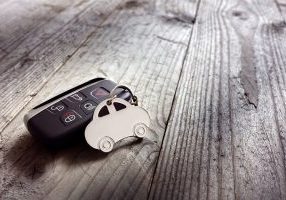 Car shape keyring and keyless entry remote on wood background